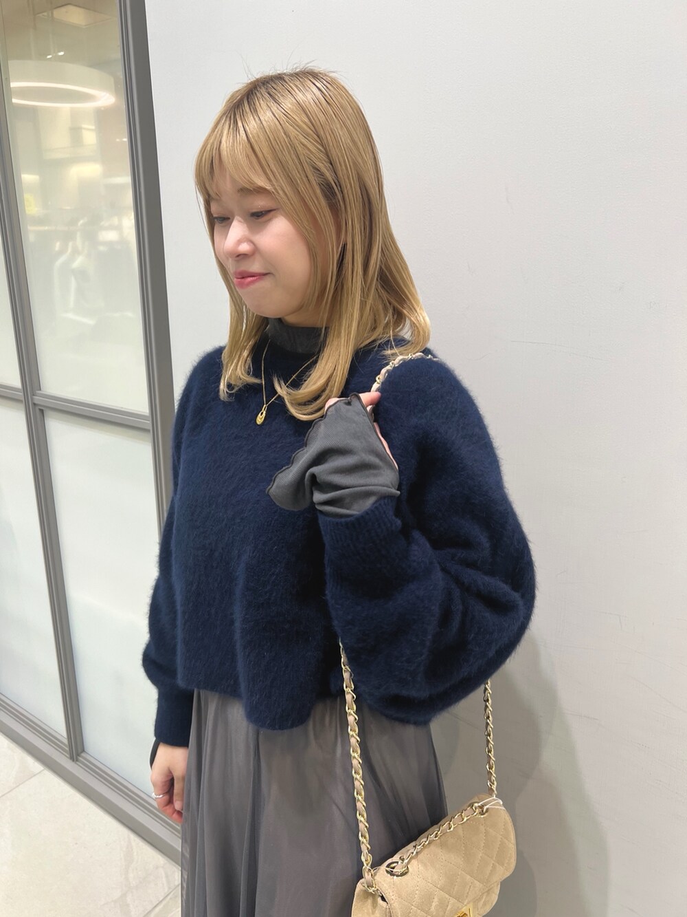 ブラック系のブーツ、グレー系のスカート、ベージュ系のショルダーバッグを着用したレディースの冬コーディネートの3枚目の写真