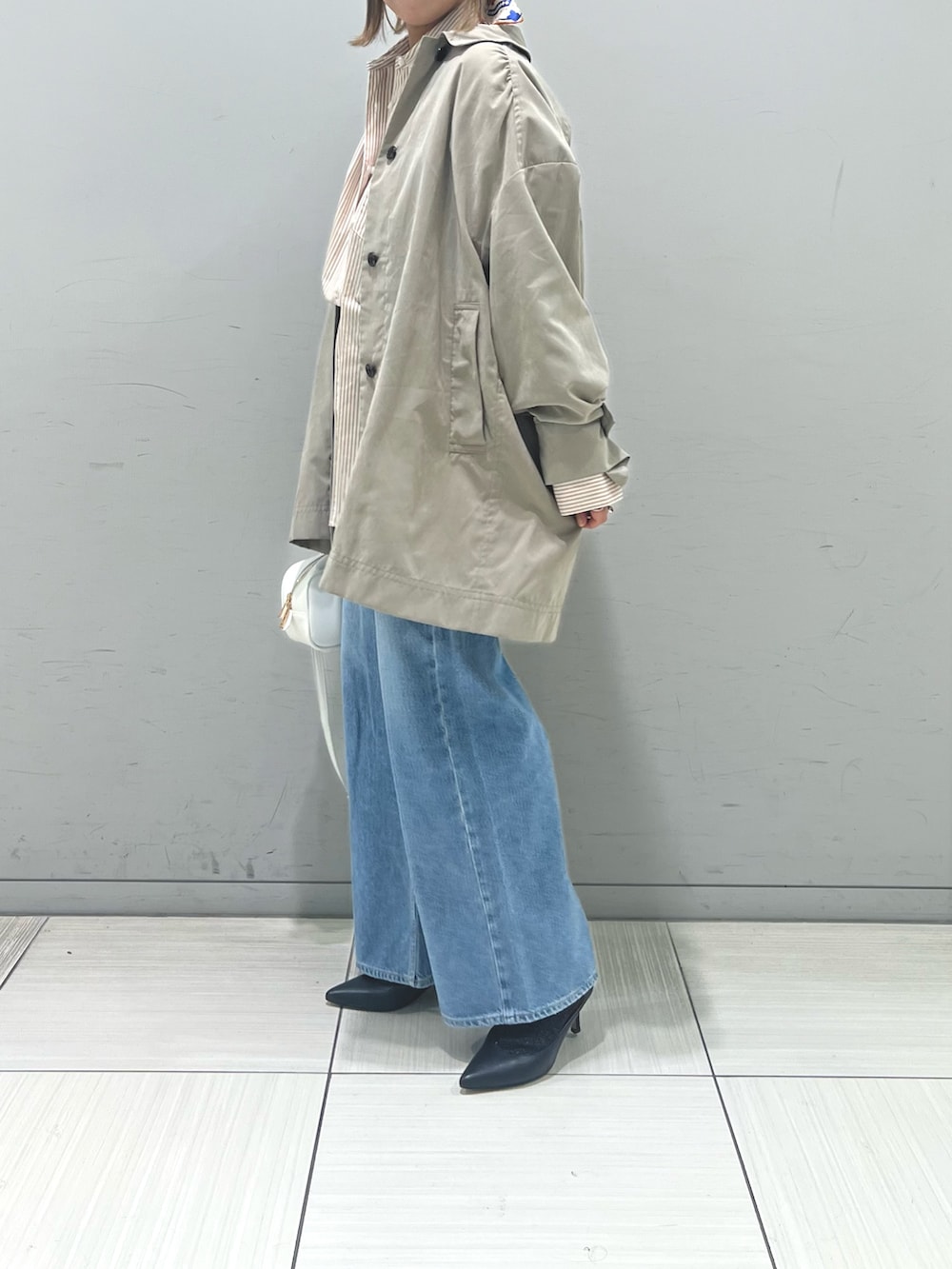 ブルー系のデニムパンツ、ホワイト系のショルダーバッグ、ベージュ系のシャツ/ブラウスを着用したレディースの冬コーディネートの2枚目の写真