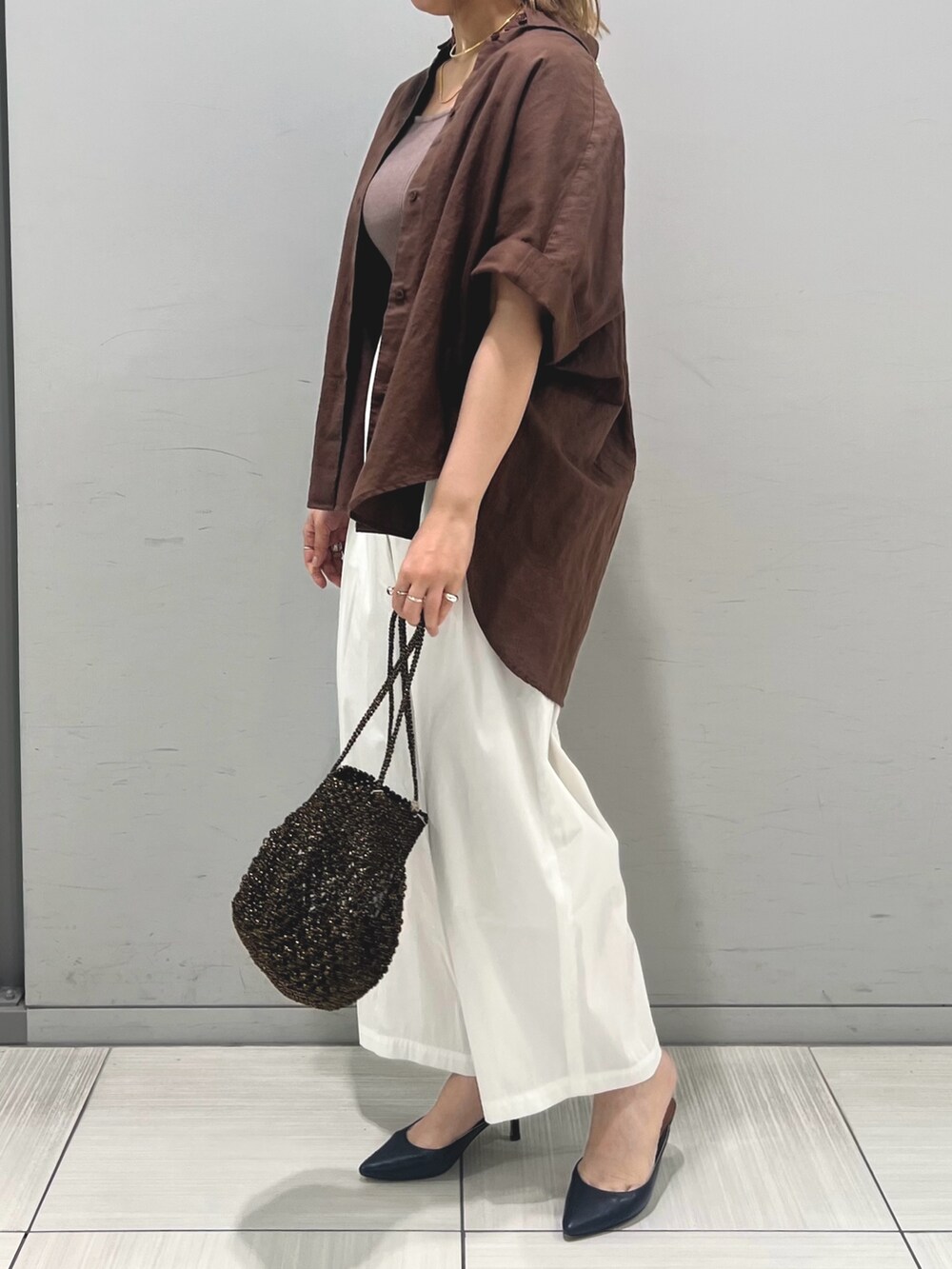 ブラック系のタンクトップ、ホワイト系のその他パンツ、ブラック系のショルダーバッグを着用したレディースの夏コーディネートの3枚目の写真