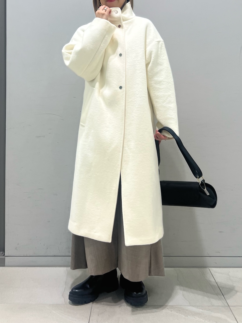 ブラック系のショルダーバッグ、ブラック系のブーツ、ホワイト系のその他アウターを着用したレディースの冬コーディネートの5枚目の写真