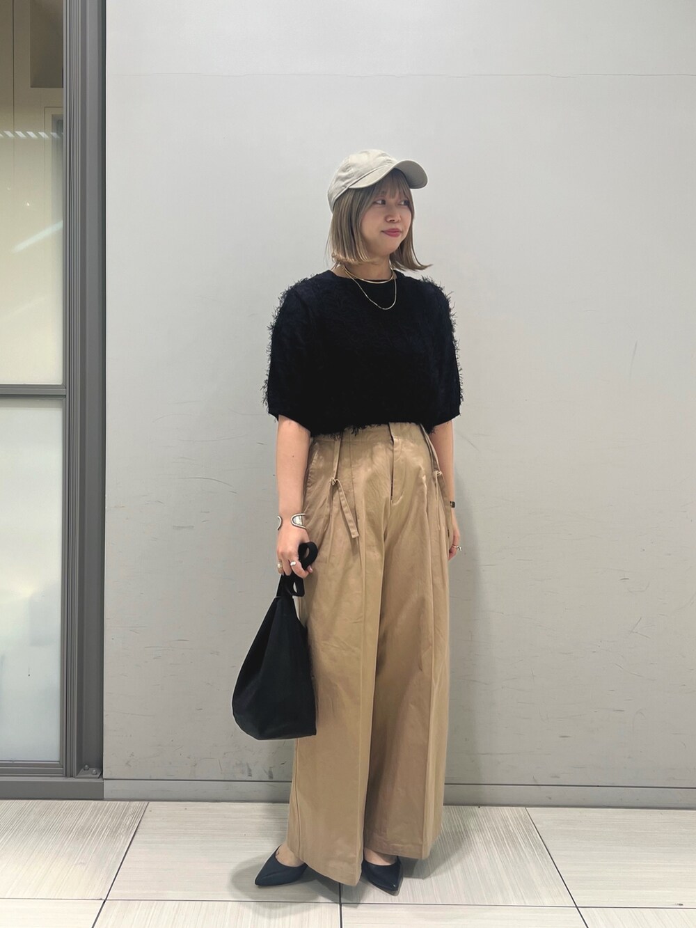 ブラック系のニット/セーター、ベージュ系のその他パンツ、ブラック系のトートバッグを着用したレディースの春コーディネートの3枚目の写真