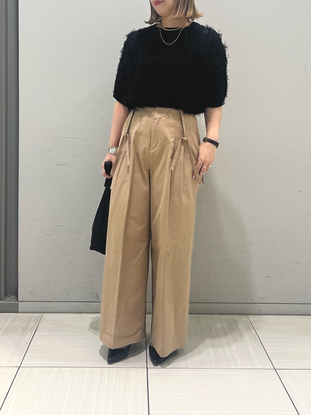 ブラック系のニット/セーター、ベージュ系のその他パンツ、ブラック系のトートバッグを着用したレディースの春コーディネートの7枚目の写真
