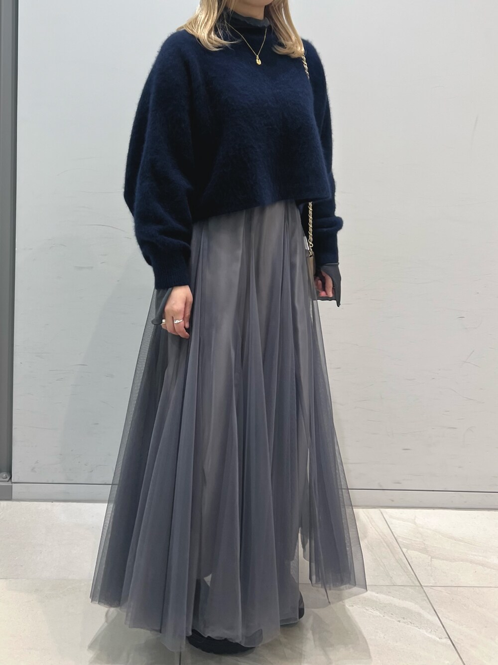 ブラック系のブーツ、グレー系のスカート、ベージュ系のショルダーバッグを着用したレディースの冬コーディネートの5枚目の写真