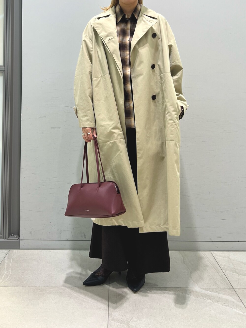 レッド系のショルダーバッグ、ブラウン系のシャツ/ブラウス、ベージュ系のステンカラーコートを着用したレディースの秋コーディネートの3枚目の写真