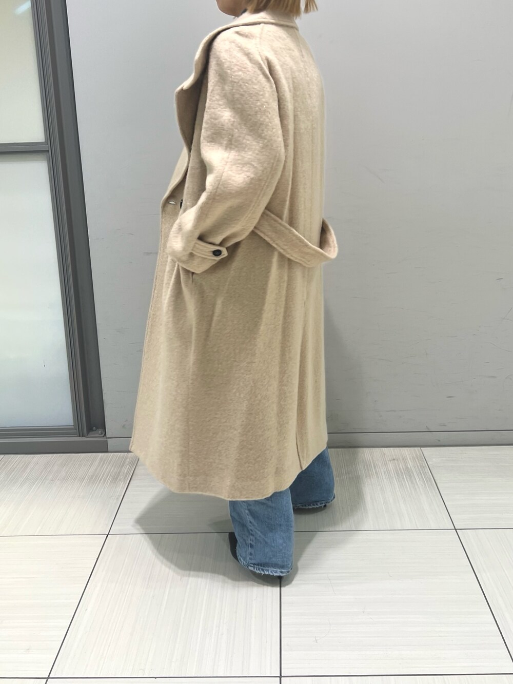 ブルー系のデニムパンツ、ブラウン系のワンピース、ベージュ系のその他アウターを着用したレディースの冬コーディネートの5枚目の写真