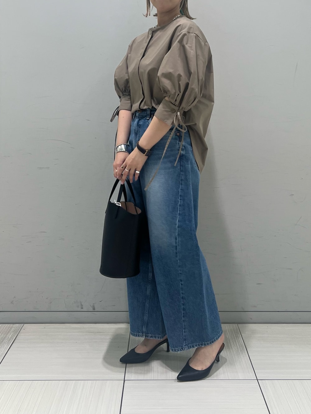 ブラウン系のシャツ/ブラウス、ブルー系のデニムパンツ、ブラック系のハンドバッグを着用したレディースの春コーディネートの2枚目の写真