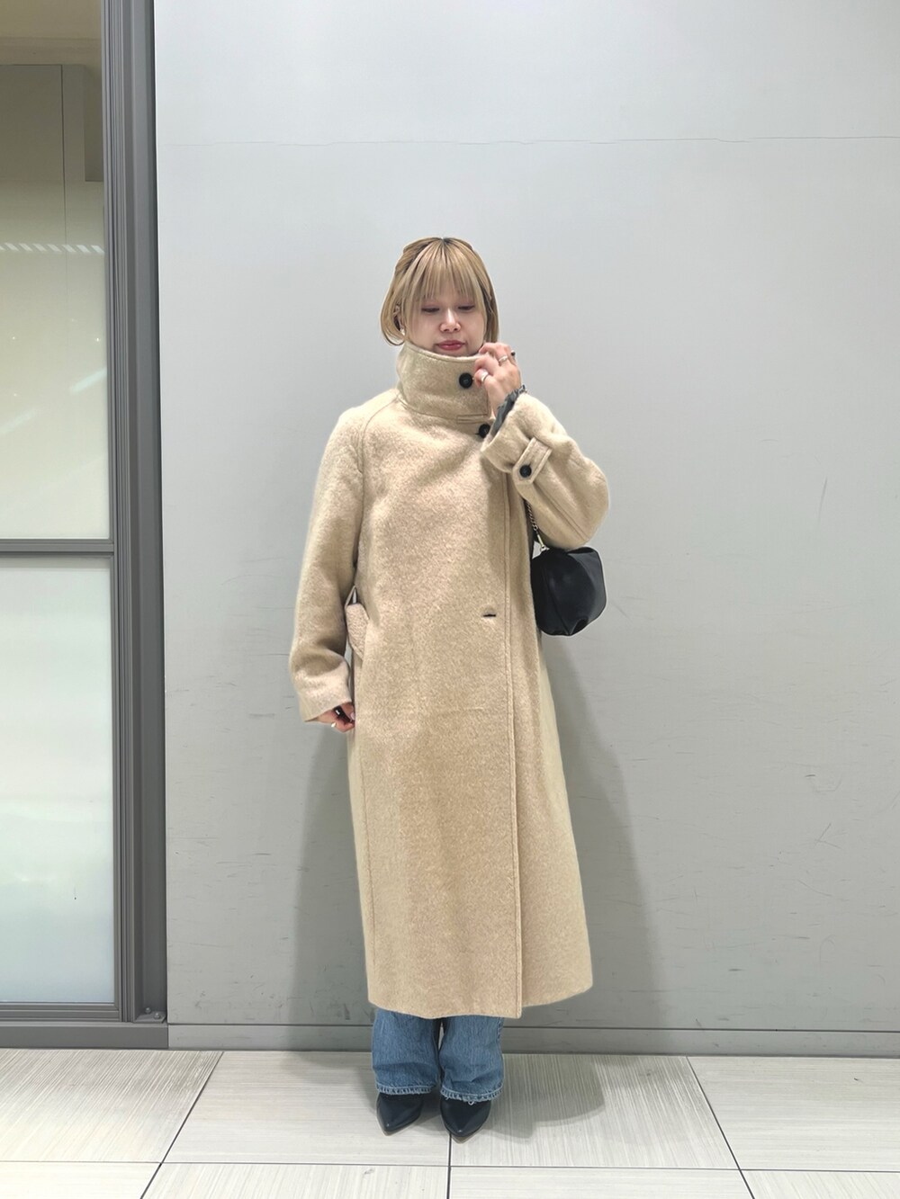 ブルー系のデニムパンツ、ブラウン系のワンピース、ベージュ系のその他アウターを着用したレディースの冬コーディネートの7枚目の写真