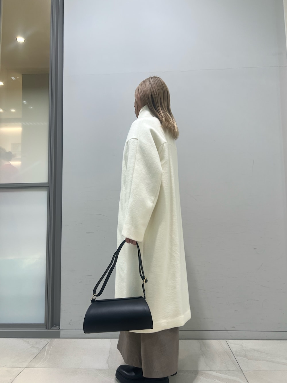 ブラック系のショルダーバッグ、ブラック系のブーツ、ホワイト系のその他アウターを着用したレディースの冬コーディネートの6枚目の写真