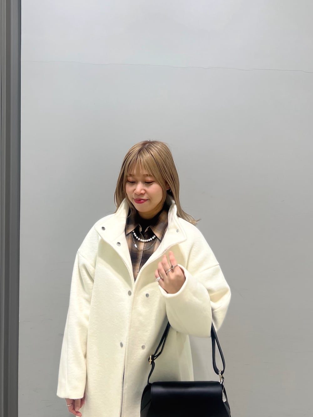 ブラック系のショルダーバッグ、ブラック系のブーツ、ホワイト系のその他アウターを着用したレディースの冬コーディネートの8枚目の写真