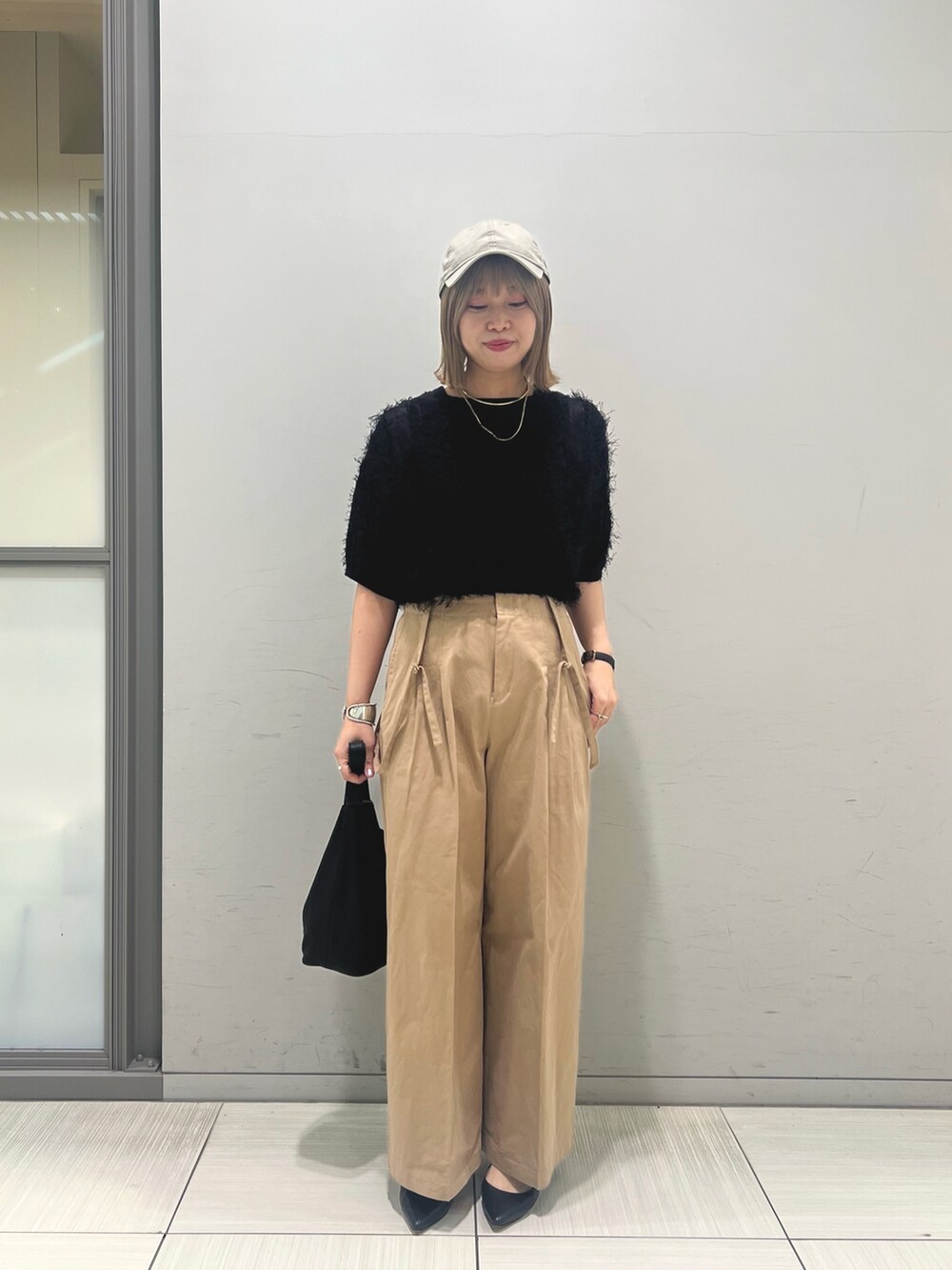 ブラック系のニット/セーター、ベージュ系のその他パンツ、ブラック系のトートバッグを着用したレディースの春コーディネートの2枚目の写真