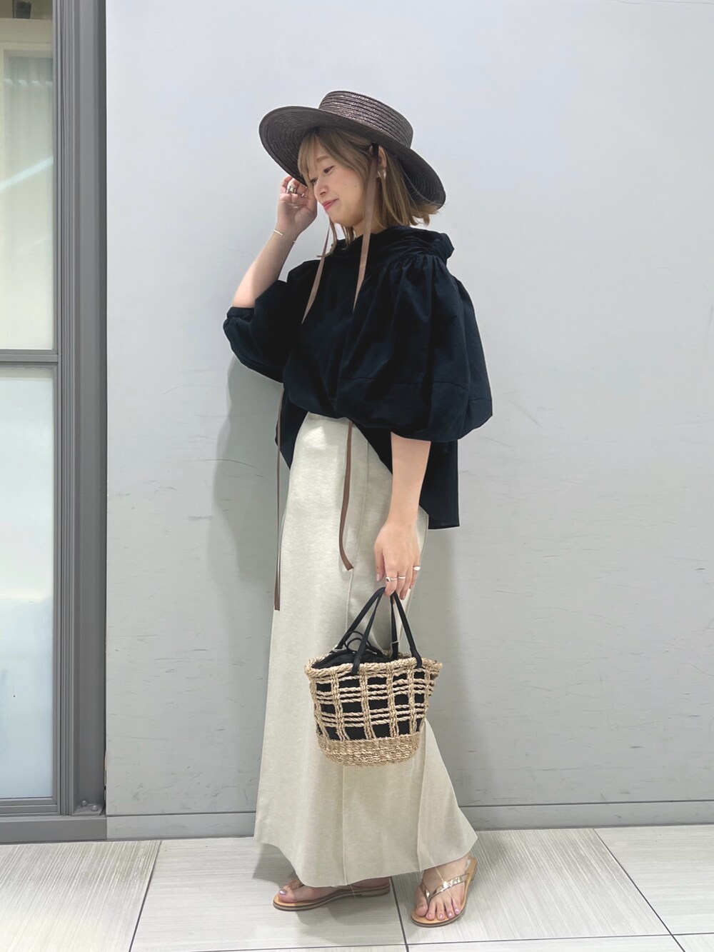 ベージュ系のかごバッグ、ゴールド系のサンダル、ブラック系のシャツ/ブラウスを着用したレディースの春コーディネートの3枚目の写真