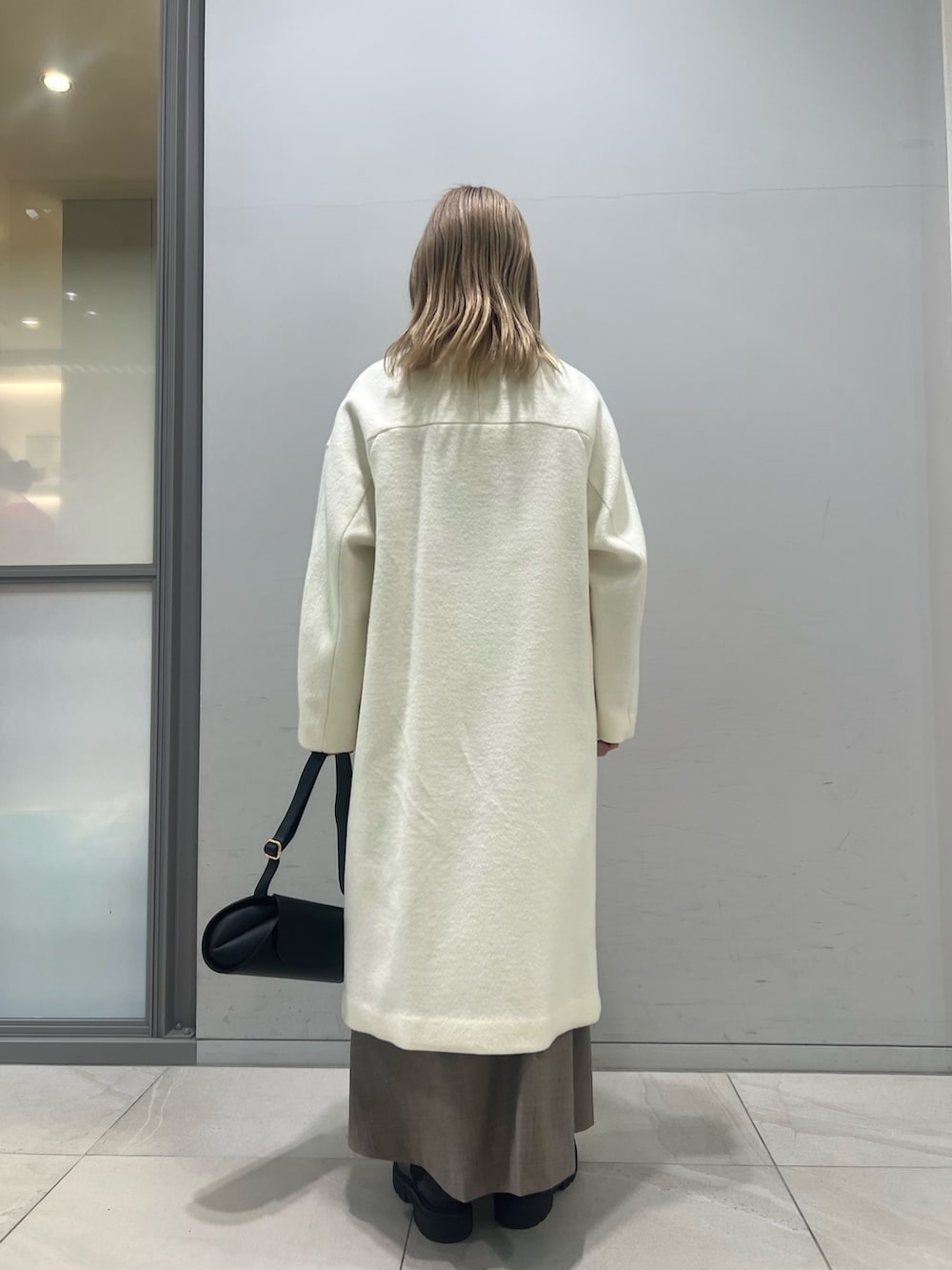 ブラック系のショルダーバッグ、ブラック系のブーツ、ホワイト系のその他アウターを着用したレディースの冬コーディネートの7枚目の写真