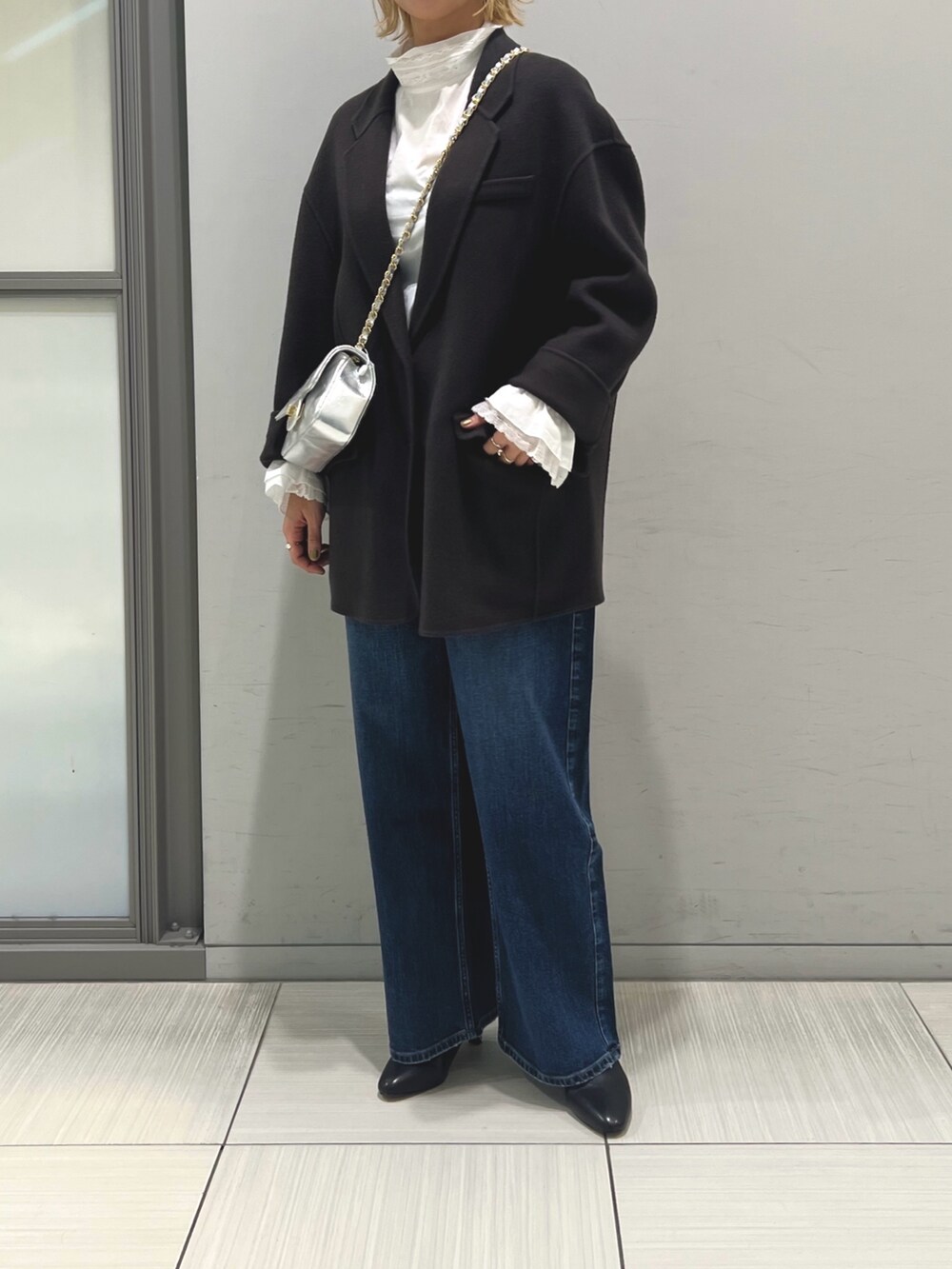 ブルー系のチェスターコート、ホワイト系のシャツ/ブラウス、ブルー系のデニムパンツを着用したレディースの秋コーディネートの5枚目の写真