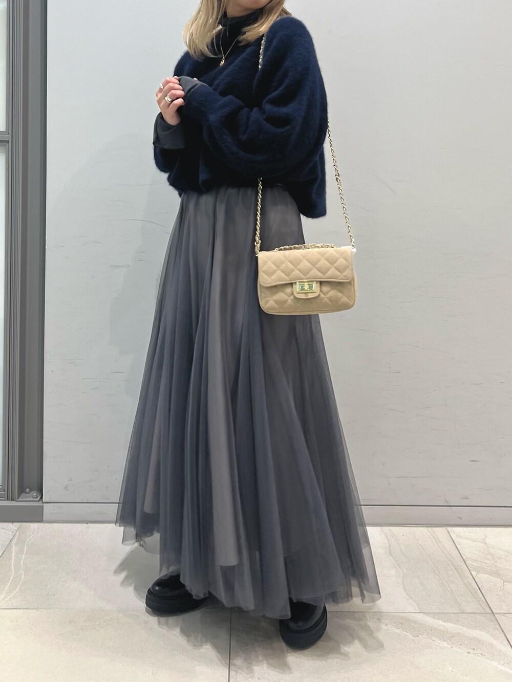 ブラック系のブーツ、グレー系のスカート、ベージュ系のショルダーバッグを着用したレディースの冬コーディネートの6枚目の写真