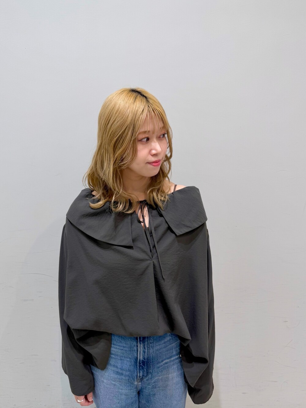 ブルー系のデニムパンツ、オレンジ系のショルダーバッグ、グレー系のシャツ/ブラウスを着用したレディースの春コーディネートの2枚目の写真