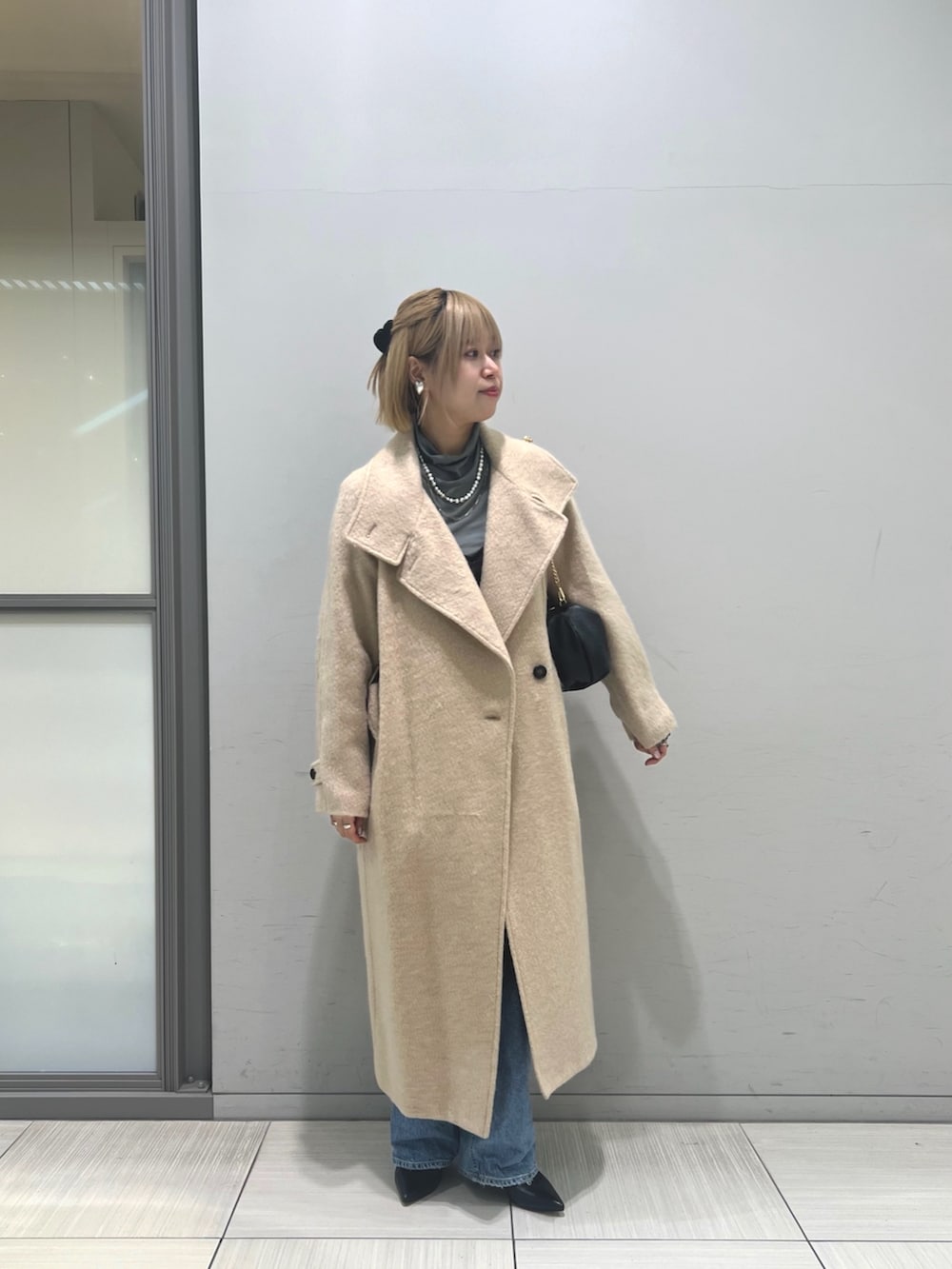 ブルー系のデニムパンツ、ブラウン系のワンピース、ベージュ系のその他アウターを着用したレディースの冬コーディネートの2枚目の写真