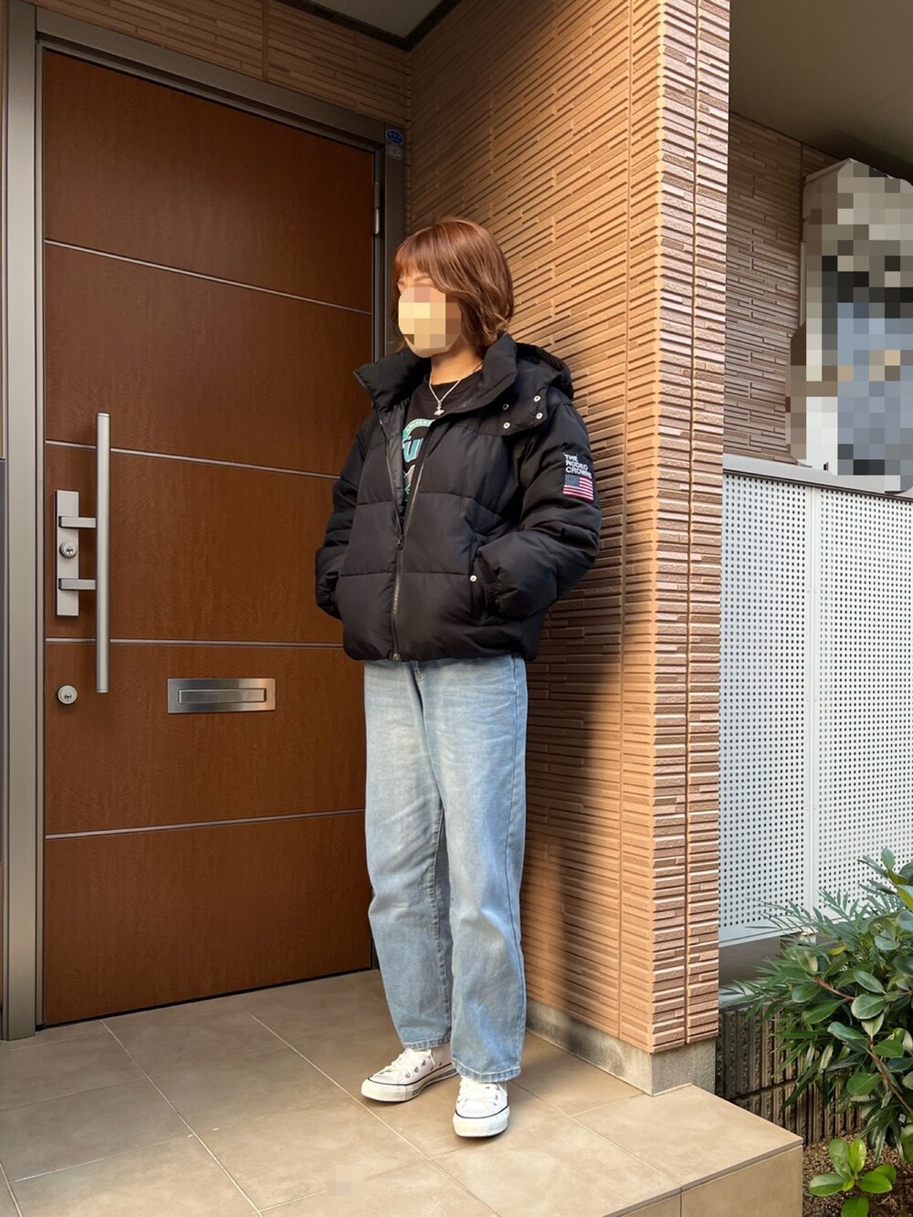 ブルー系のデニムパンツ、ホワイト系のスニーカー、ブラック系のダウンジャケット/コートを着用したレディースの冬コーディネートの2枚目の写真