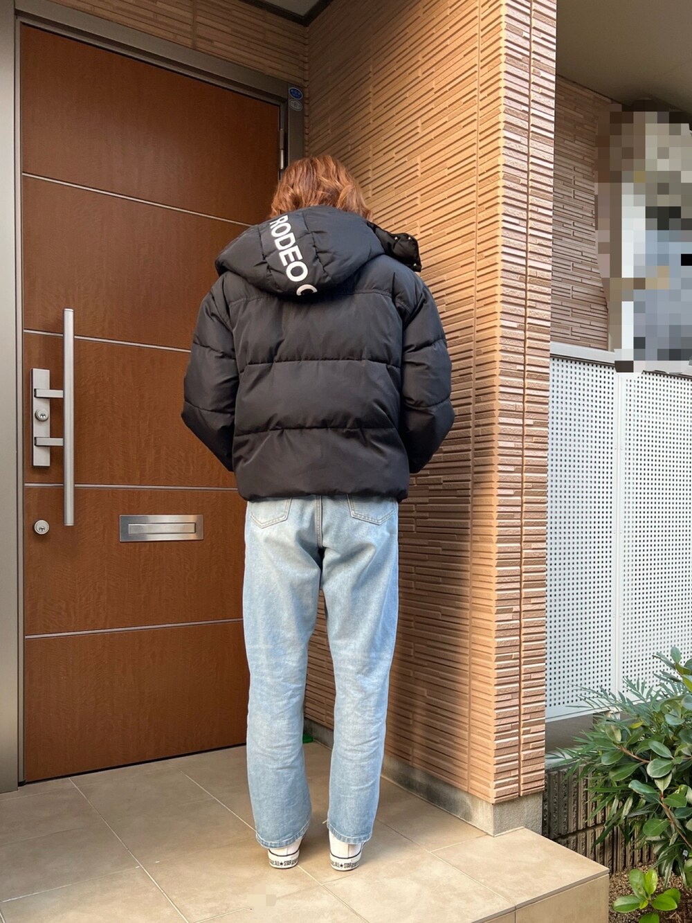 ブルー系のデニムパンツ、ホワイト系のスニーカー、ブラック系のダウンジャケット/コートを着用したレディースの冬コーディネートの3枚目の写真