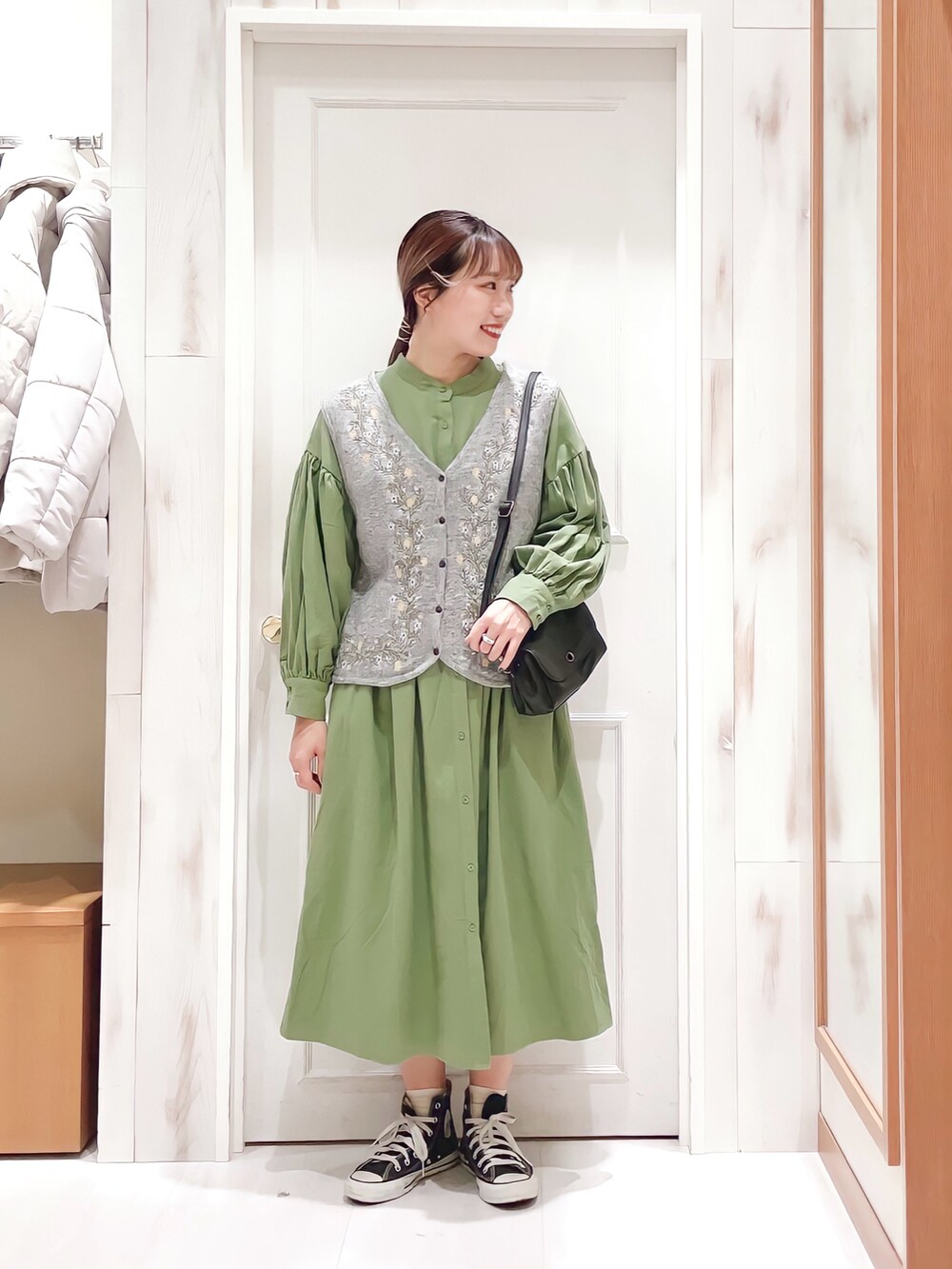 グリーン系のワンピース、グレー系のベスト、ブラック系のショルダーバッグを着用したレディースの冬コーディネートの3枚目の写真
