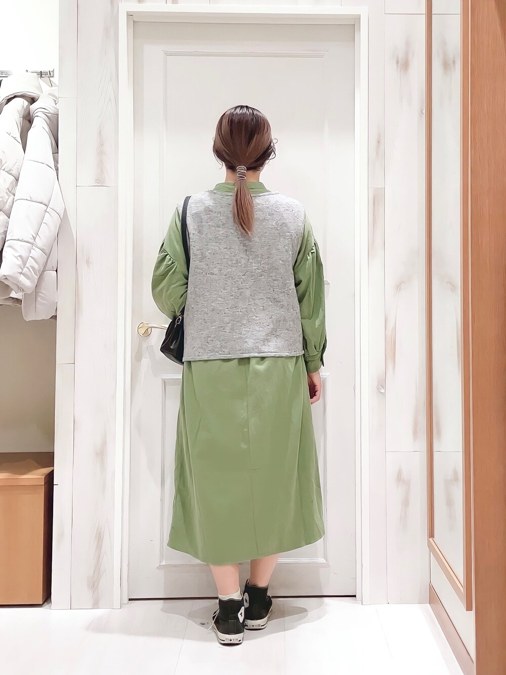 グリーン系のワンピース、グレー系のベスト、ブラック系のショルダーバッグを着用したレディースの冬コーディネートの2枚目の写真