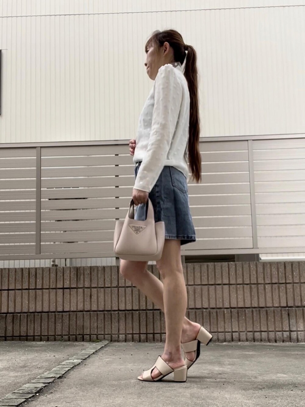 ブルー系のデニムスカート、ホワイト系のシャツ/ブラウスを着用したレディースの春コーディネートの2枚目の写真