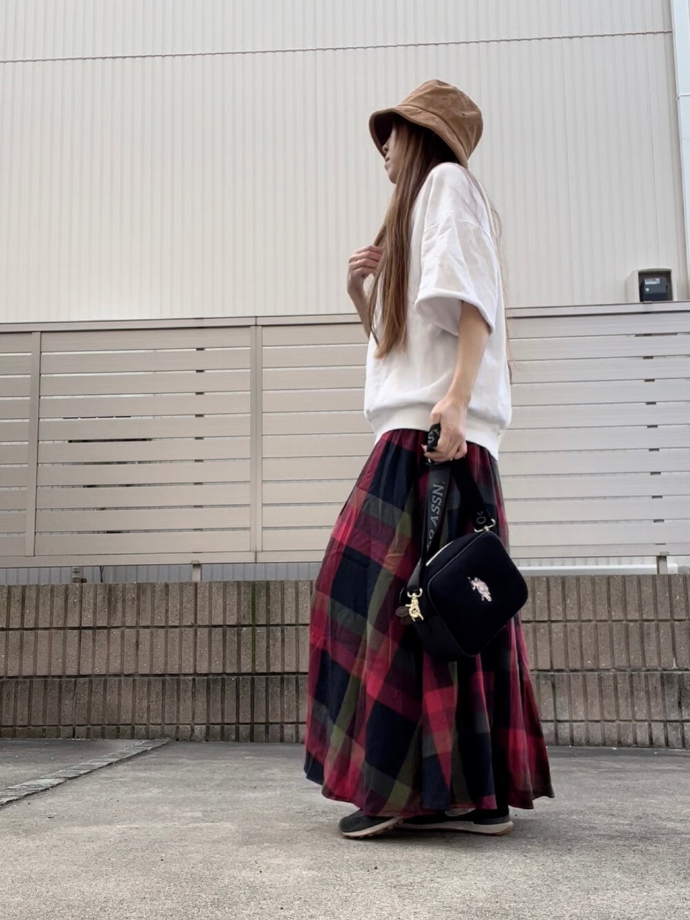 レッド系のスカート、ブラック系のショルダーバッグを着用したレディースの秋コーディネートの3枚目の写真