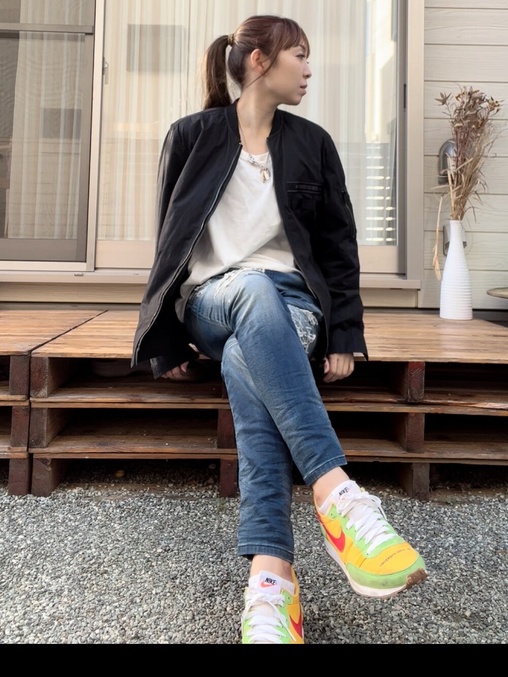 ブラック系のジャケット/アウター、ブルー系のデニムパンツ、イエロー系のスニーカーを着用したレディースの秋コーディネートの2枚目の写真