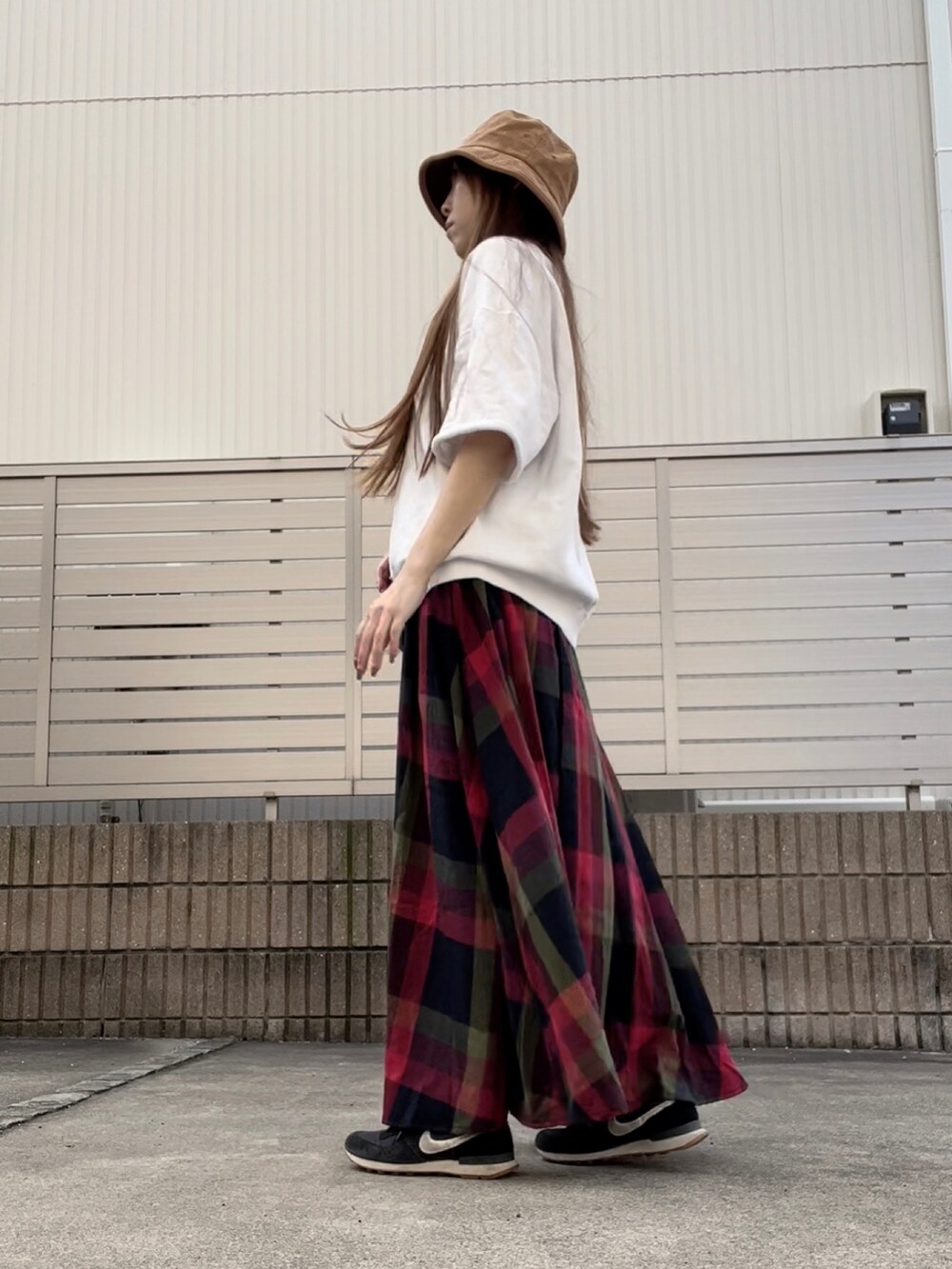 レッド系のスカート、ブラック系のショルダーバッグを着用したレディースの秋コーディネートの2枚目の写真