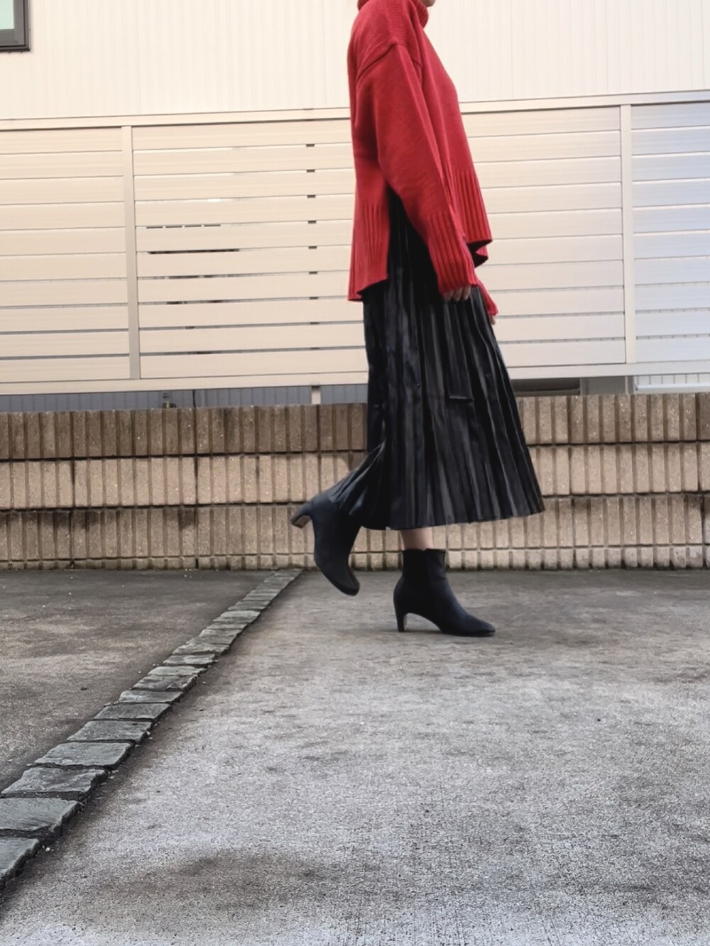 ブラック系のスカート、ブラック系のブーツ、オレンジ系のニット/セーターを着用したレディースの秋コーディネートの3枚目の写真