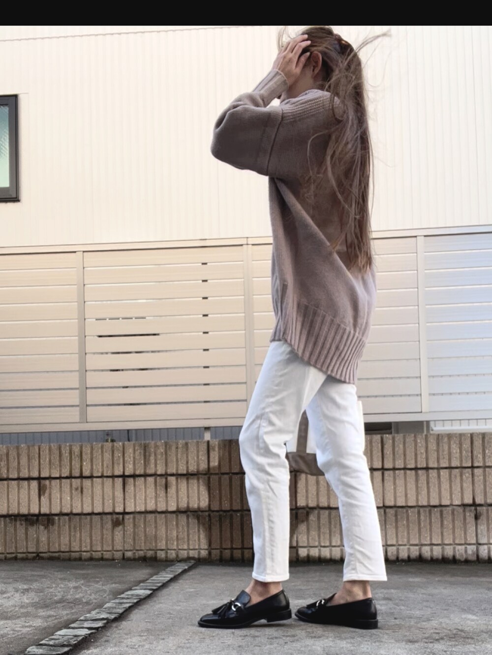 ブラウン系のニット/セーター、ホワイト系のパンツ、ブラック系のローファーを着用したレディースの秋コーディネートの2枚目の写真