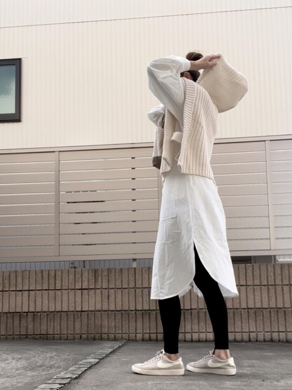 ベージュ系のニット/セーター、ホワイト系のシャツワンピース、ブラック系のレギンス/スパッツを着用したレディースの秋コーディネートの2枚目の写真