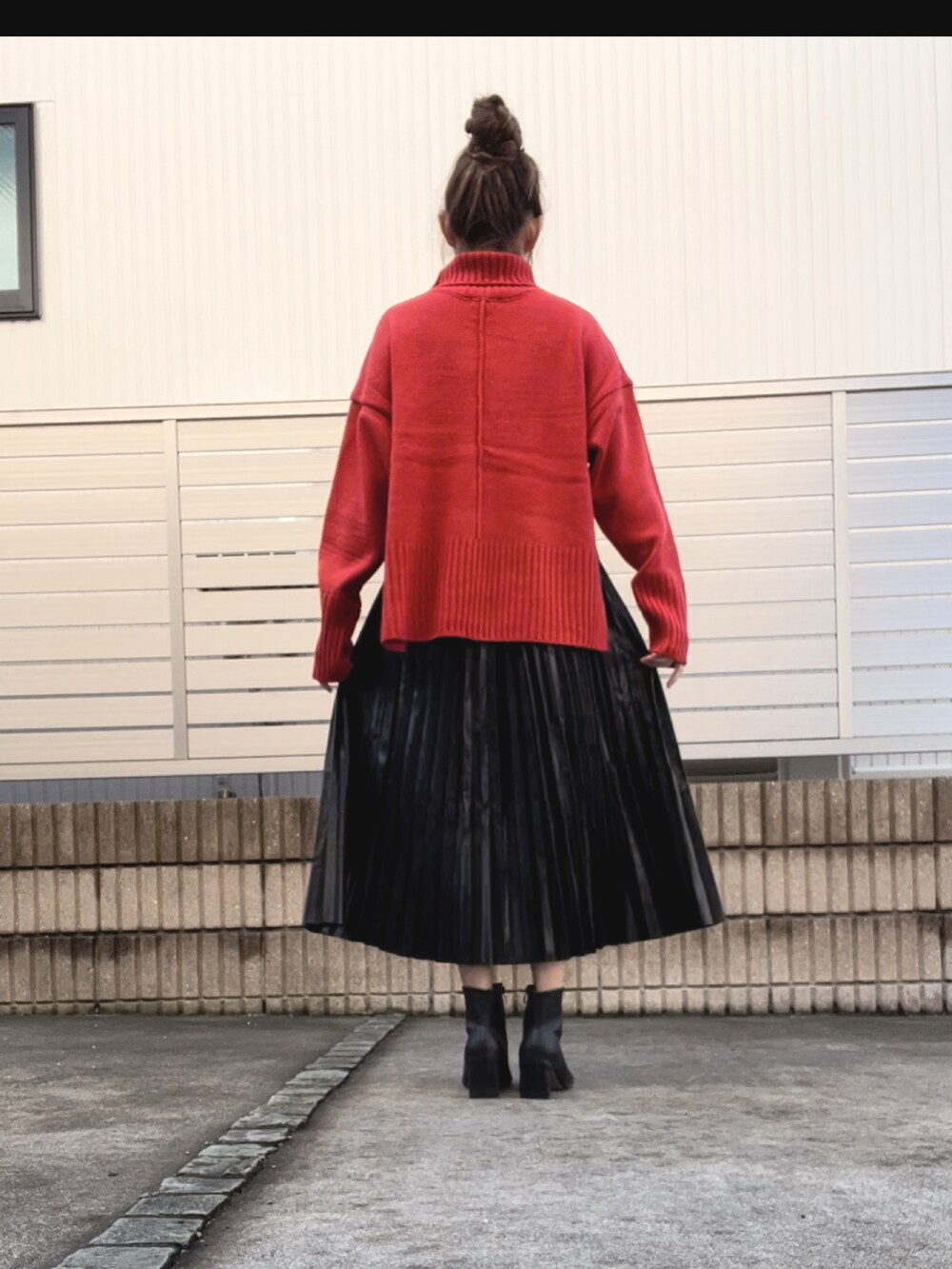 ブラック系のスカート、ブラック系のブーツ、オレンジ系のニット/セーターを着用したレディースの秋コーディネートの2枚目の写真