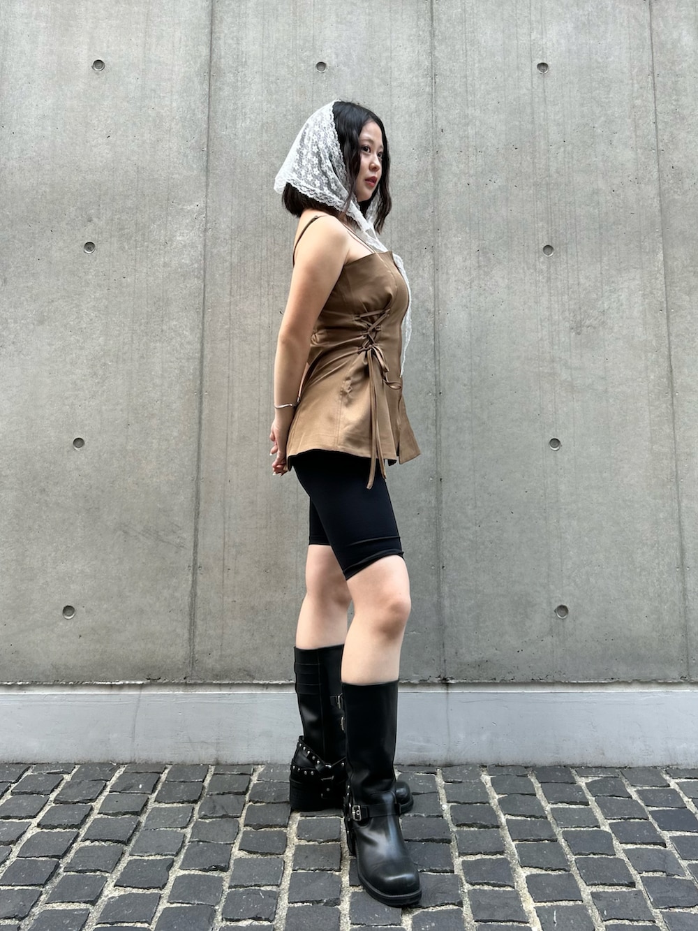 ブラウン系のキャミソール、ブラック系のブーツを着用したレディースの夏コーディネートの2枚目の写真