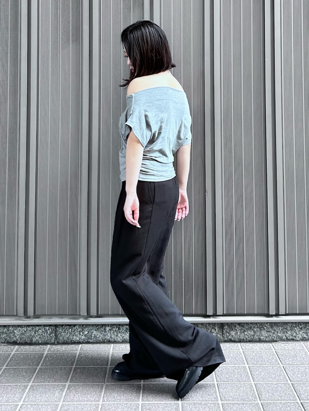 ブラック系のスラックス、グレー系のTシャツ/カットソー、ブラック系のローファーを着用したレディースの夏コーディネートの2枚目の写真