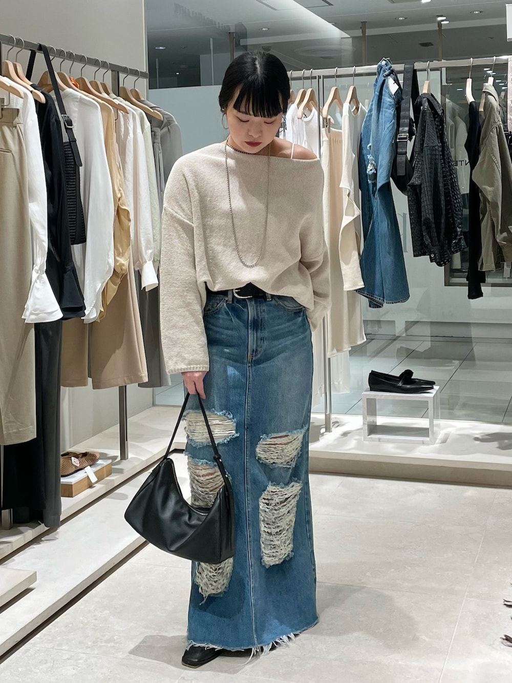 ベージュ系のニット/セーター、ブルー系のスカート、ブラック系のトートバッグを着用したレディースの春コーディネートの2枚目の写真