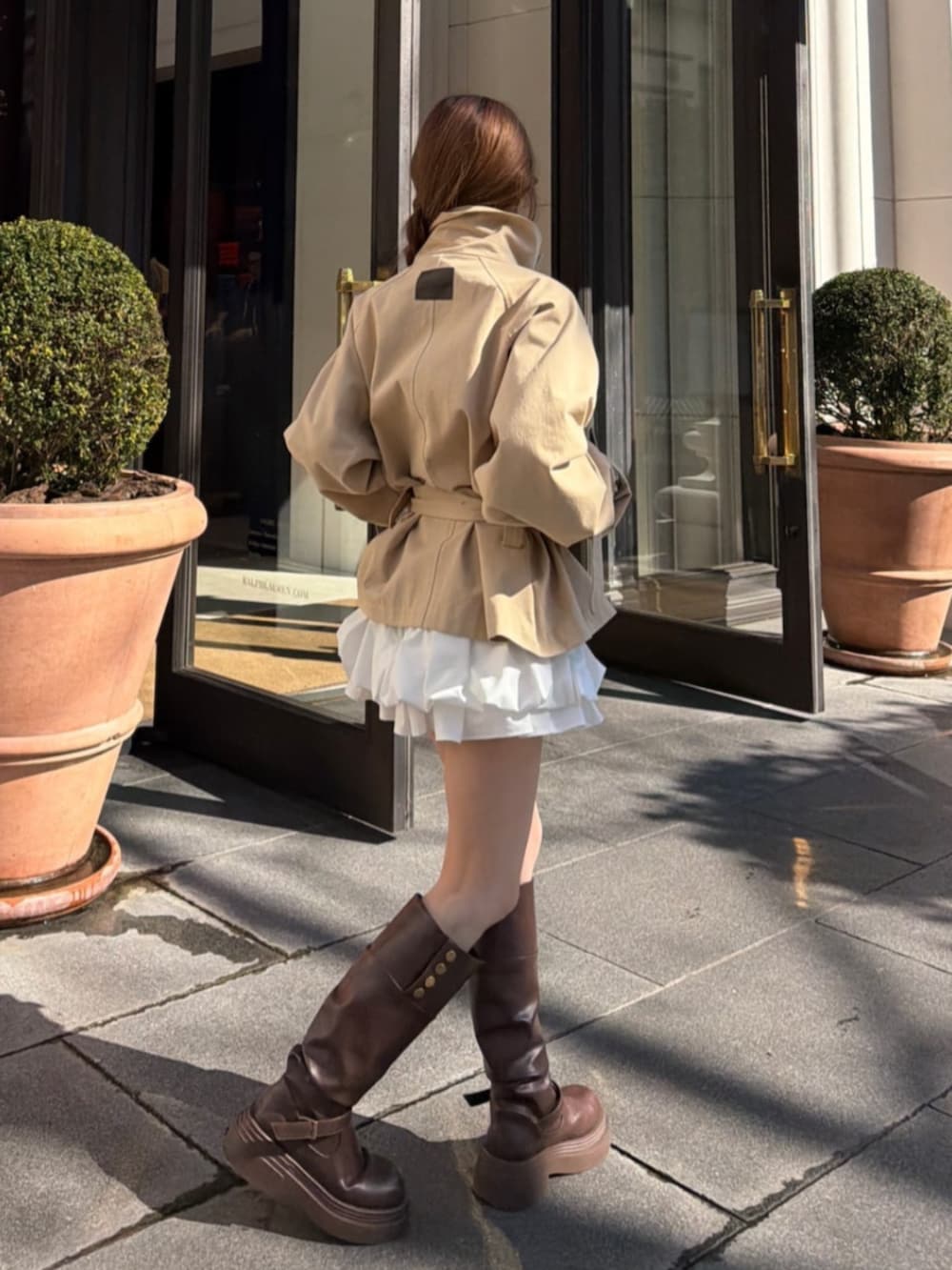 ベージュ系のトレンチコートを着用したレディースの冬コーディネートの2枚目の写真