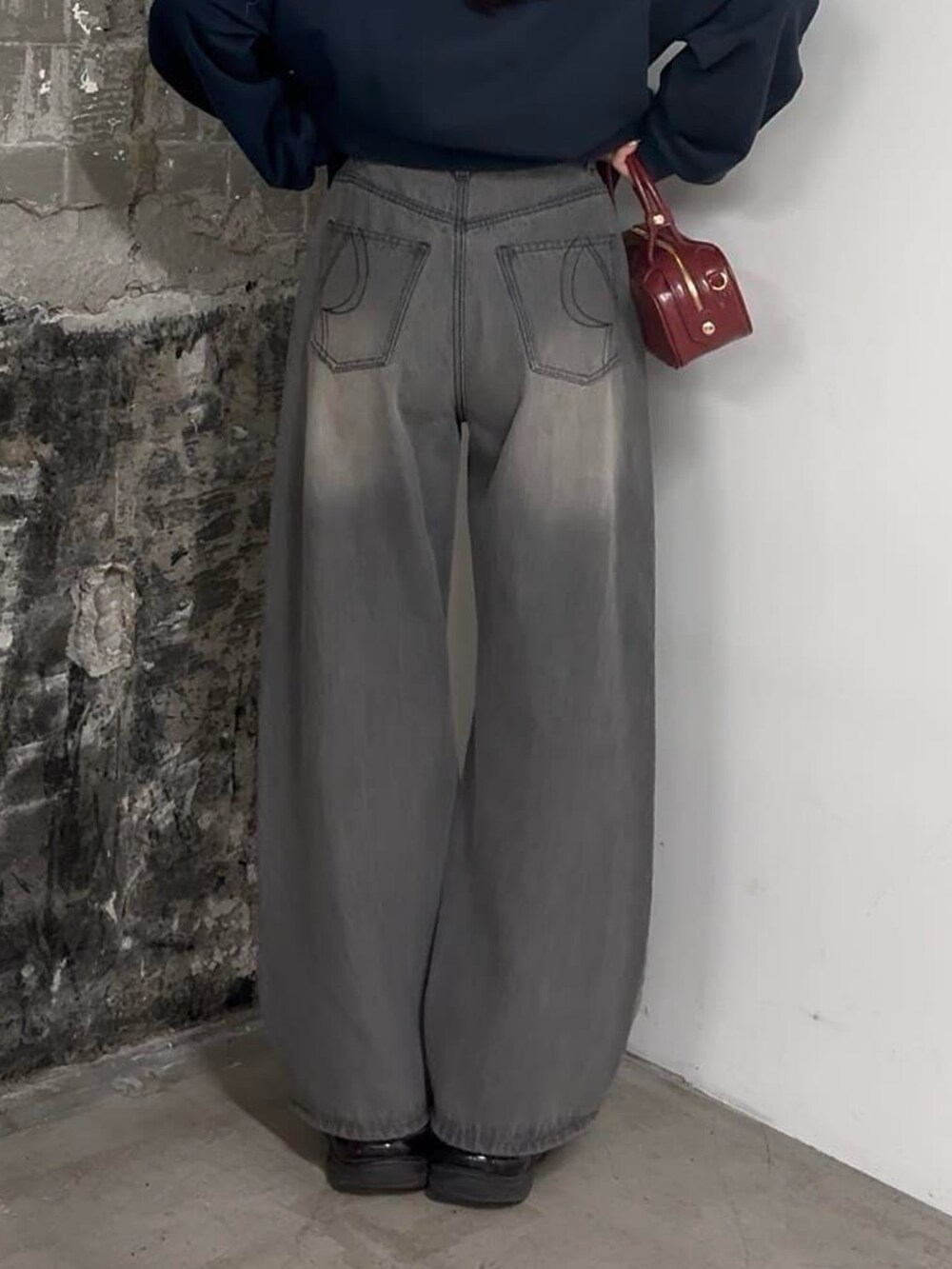 ブルー系のスウェット、グレー系のデニムパンツ、レッド系のボストンバッグを着用したレディースの冬コーディネートの2枚目の写真