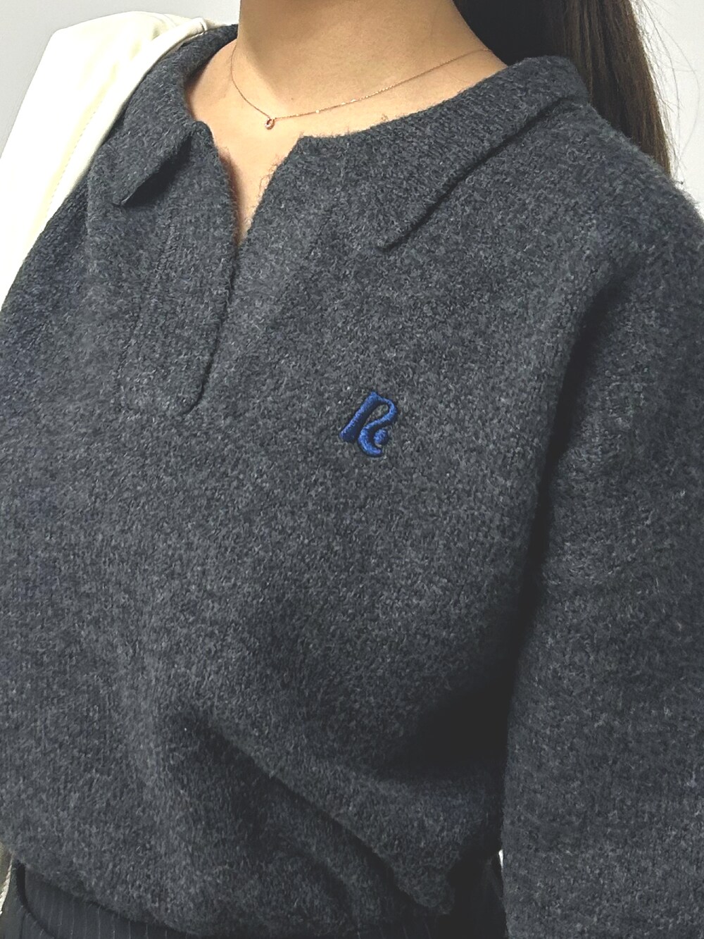 グレー系のニット/セーター、ブラック系のスカート、ホワイト系のハンドバッグを着用したレディースの秋コーディネートの3枚目の写真