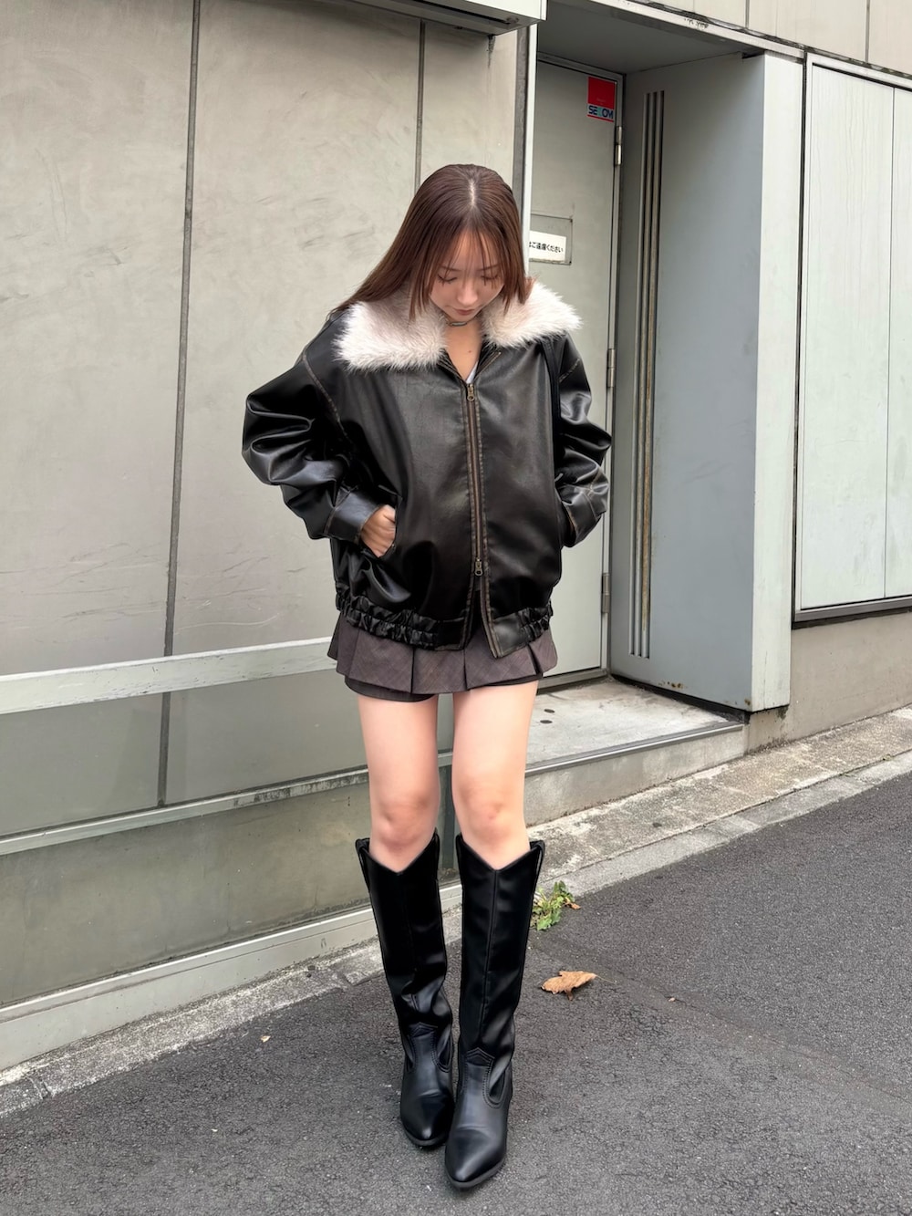 ブラック系のブルゾン、ホワイト系のTシャツ/カットソー、ブラウン系のスカートを着用したレディースの秋コーディネートの2枚目の写真