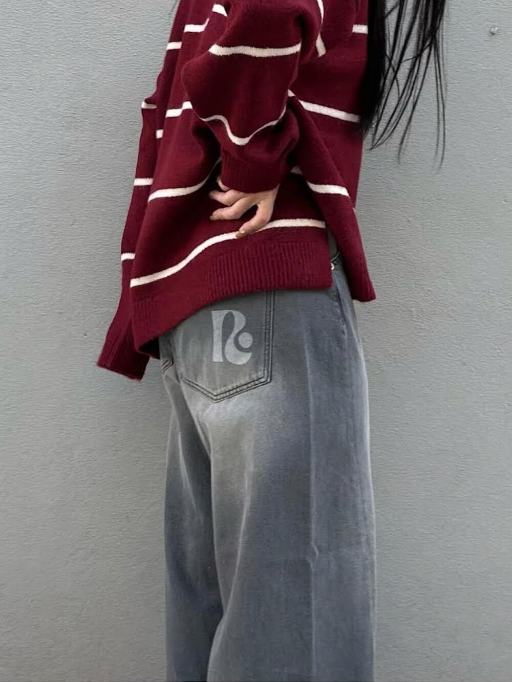レッド系のニット/セーター、グレー系のデニムパンツを着用したレディースの冬コーディネートの2枚目の写真