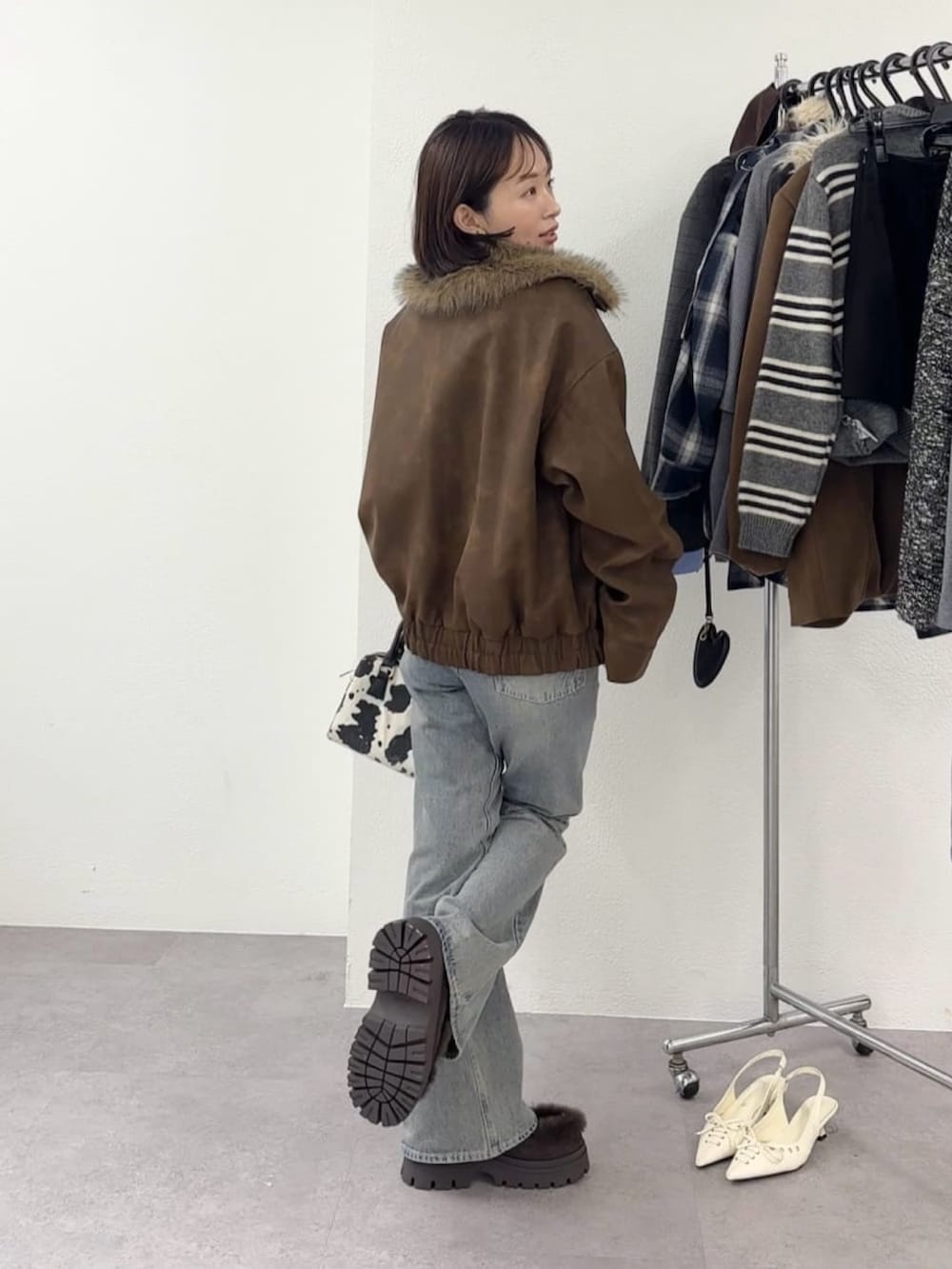 ベージュ系のブルゾン、ブルー系のデニムパンツを着用したレディースの秋コーディネートの3枚目の写真