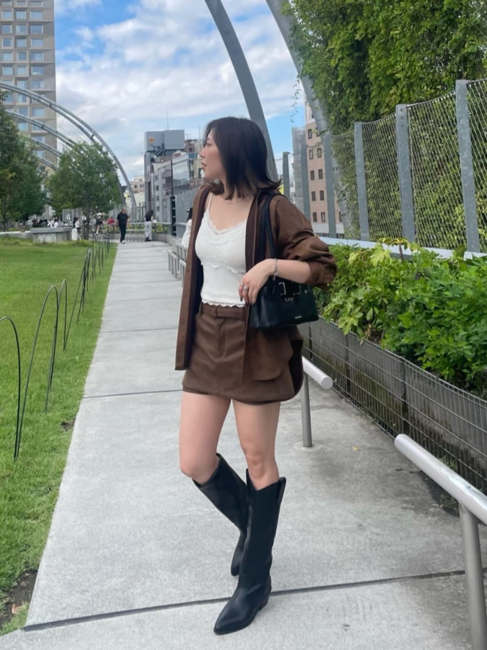 ホワイト系のキャミソール、ブラック系のショルダーバッグ、ブラック系のブーツを着用したレディースの秋コーディネートの2枚目の写真