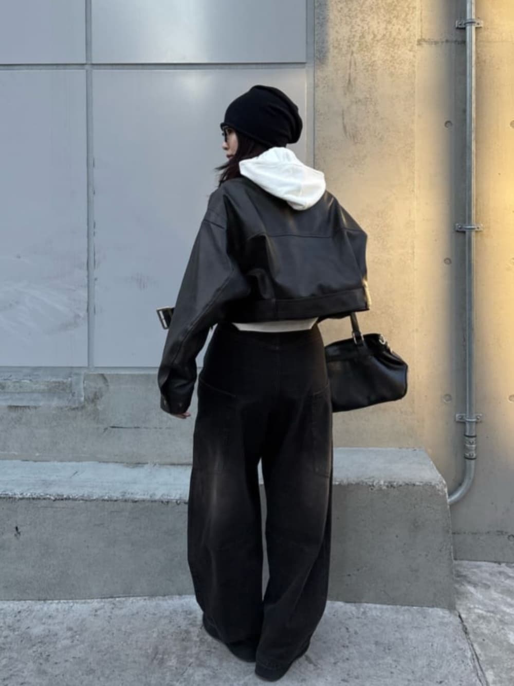 ブラック系のデニムパンツ、ブラウン系のその他アウター、ブラック系のショルダーバッグを着用したレディースの冬コーディネートの2枚目の写真