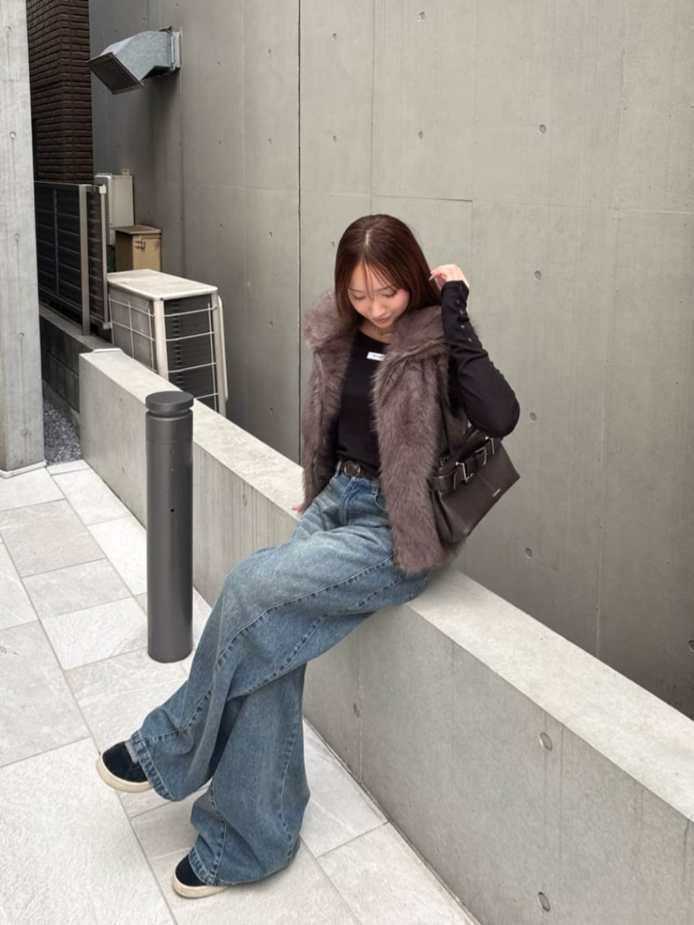 ブラウン系のショルダーバッグ、ブラック系のTシャツ/カットソー、ベージュ系のベストを着用したレディースの秋コーディネートの2枚目の写真