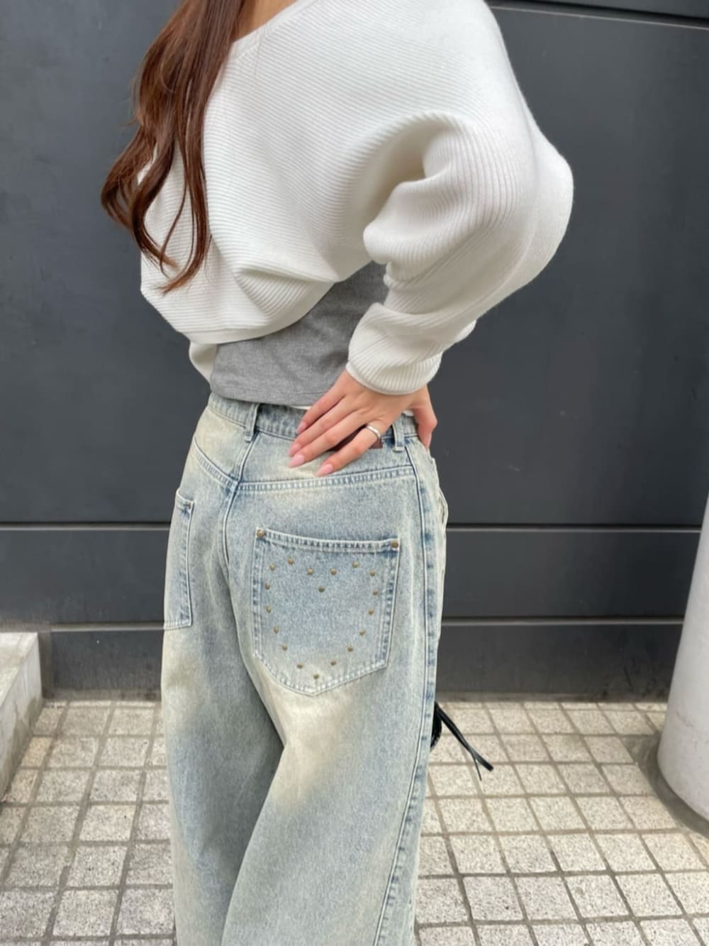 ブルー系のデニムパンツ、ブラック系のショルダーバッグ、ホワイト系のニット/セーターを着用したレディースの春コーディネートの3枚目の写真