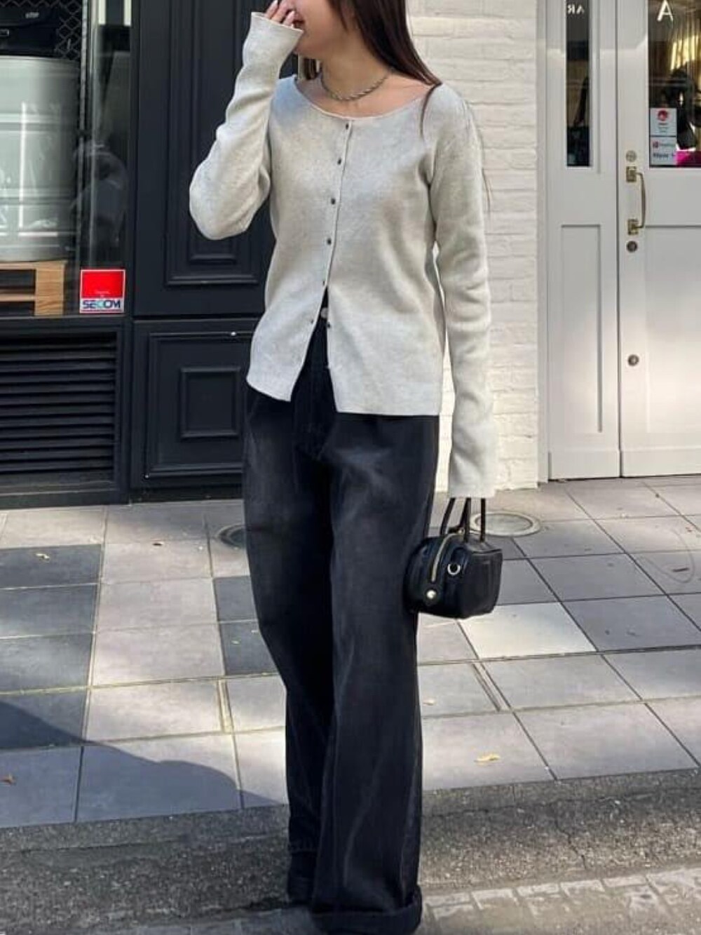 ホワイト系のカーディガン/ボレロ、ブラック系のデニムパンツ、ブラック系のボストンバッグを着用したレディースの冬コーディネートの2枚目の写真
