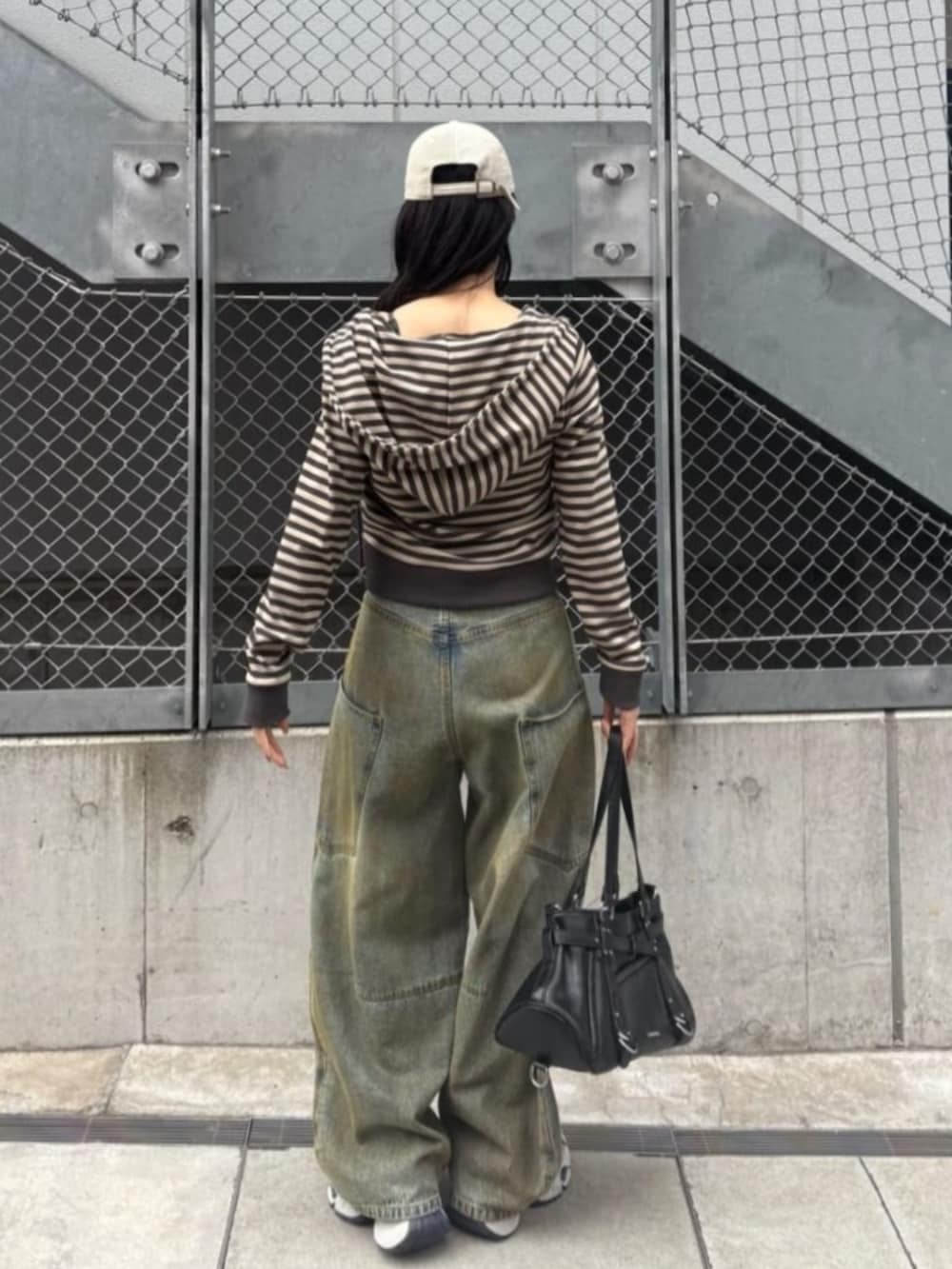 グレー系のキャミソール、ブルー系のデニムパンツ、ホワイト系のスニーカーを着用したレディースの春コーディネートの2枚目の写真
