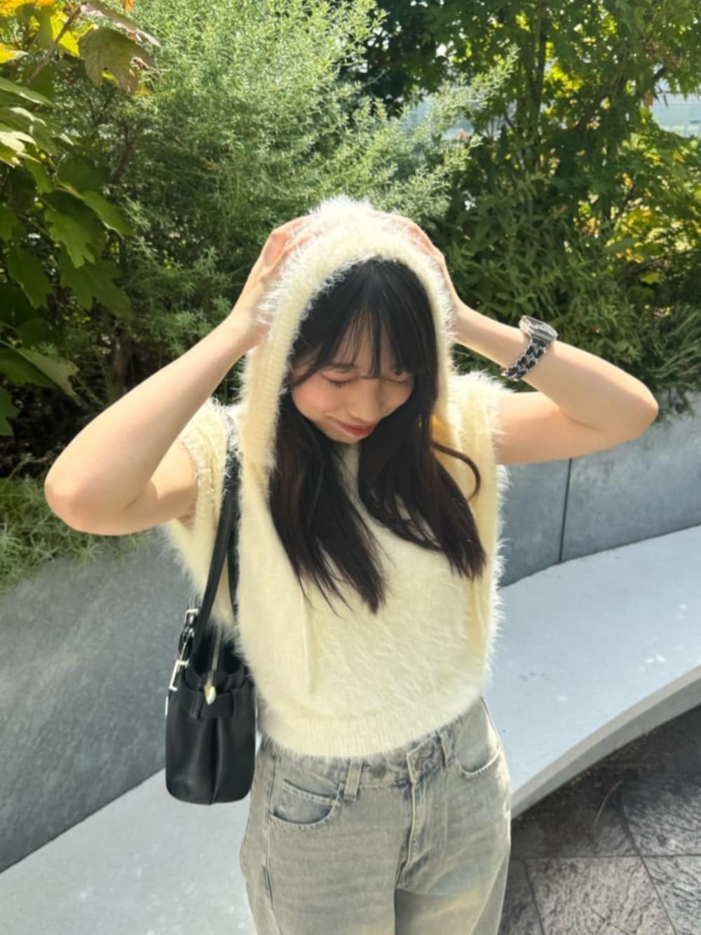 ブルー系のデニムパンツ、ブラック系のショルダーバッグ、ホワイト系のニット/セーターを着用したレディースの秋コーディネートの3枚目の写真