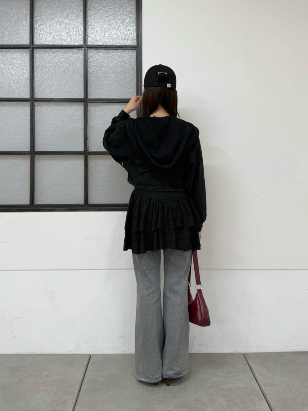 ブルー系のデニムパンツ、ブラック系のパーカー、ブラック系のワンピースを着用したレディースの春コーディネートの3枚目の写真