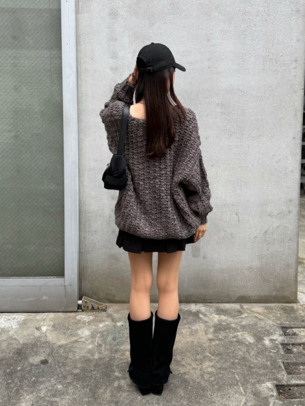 ブラック系のスカート、グレー系のニット/セーターを着用したレディースの秋コーディネートの2枚目の写真